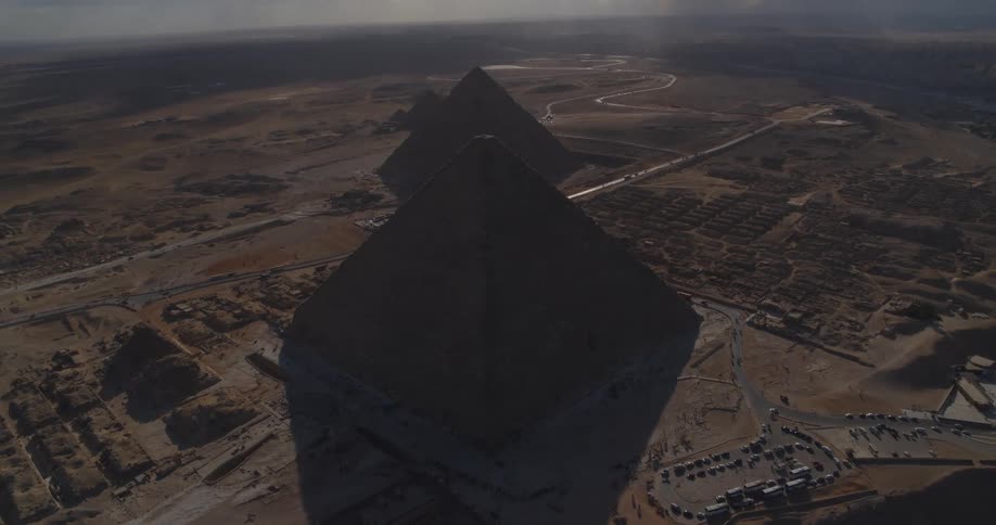 An epic aerial shot reveals the silhouetted Pyramids of Giza as the camera slowly pulls back over the vast Egyptian desert