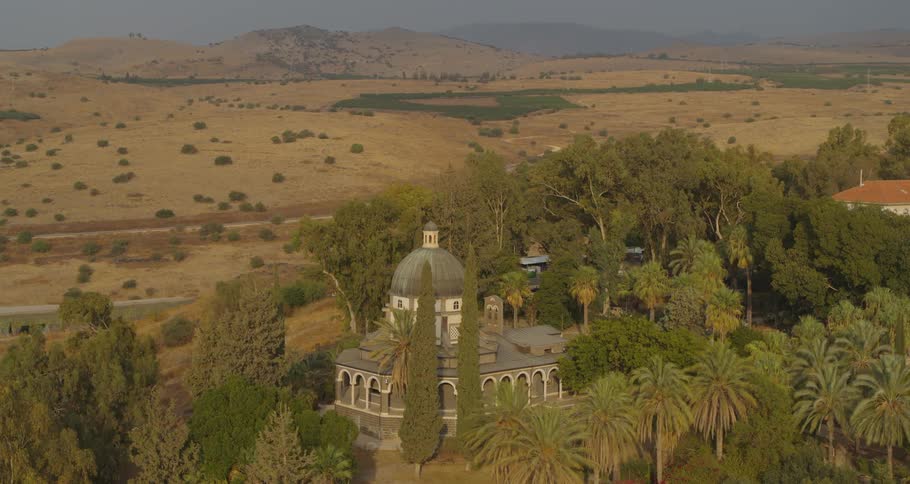An aerial view of the historic Church of the Beatitudes surrounded by lush gardens amidst the arid hills of Galilee, Israel