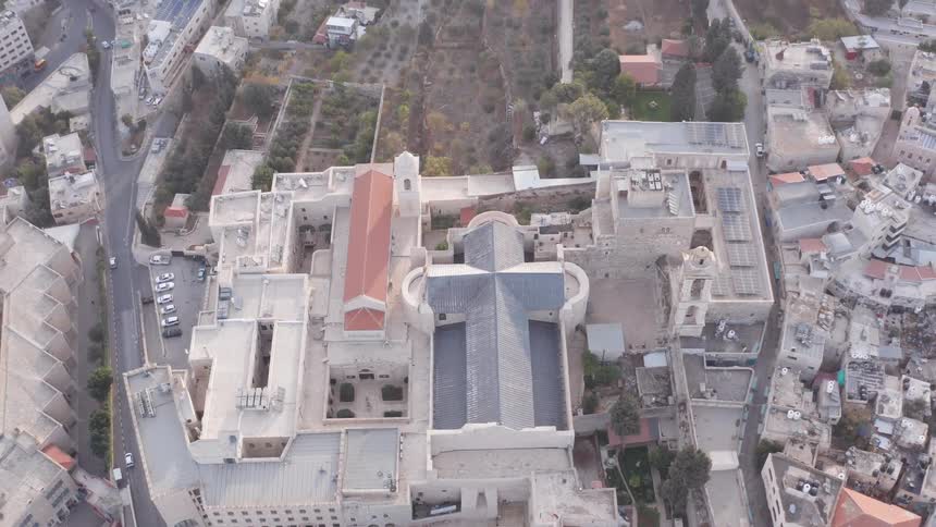 A top-down aerial view of the historic Church of the Nativity in Bethlehem slowly rises to reveal the sprawling cityscape