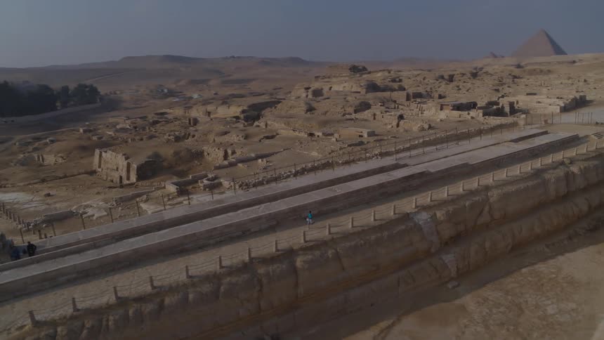 An aerial shot pans from the Great Sphinx to reveal a man running through the Giza Necropolis with the Great Pyramids in the background