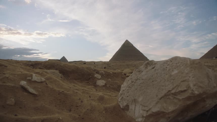 A slow pan reveals the ancient Great Pyramids of Giza standing tall in the vast Egyptian desert at dusk