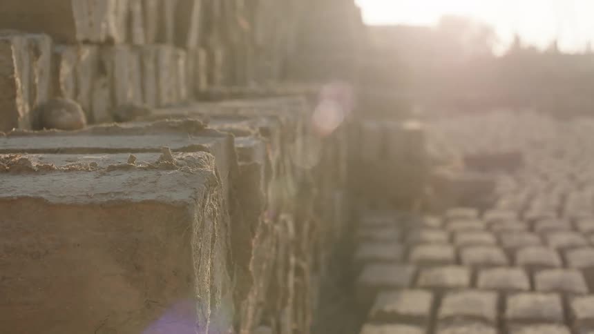 A close up shot of a large pile of freshly made clay bricks basking in the hazy morning sun to dry