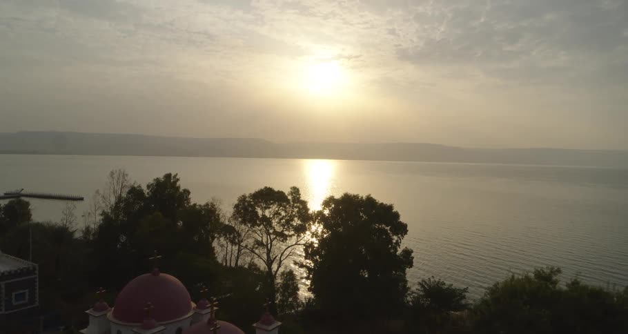 Aerial view flying over the Greek Orthodox Church of the Twelve Apostles towards the sunrise over the Sea of Galilee
