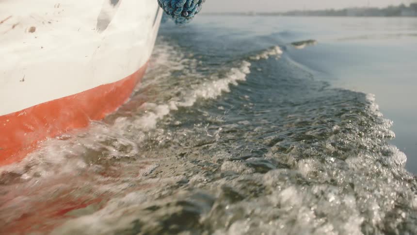 A close-up slow-motion shot of a boat creating waves as it glides across the water
