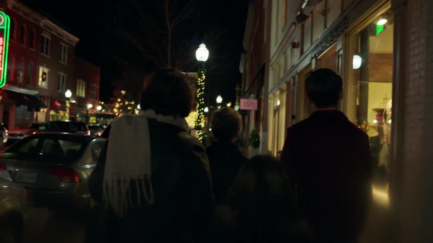 Three people walk down a city street at night