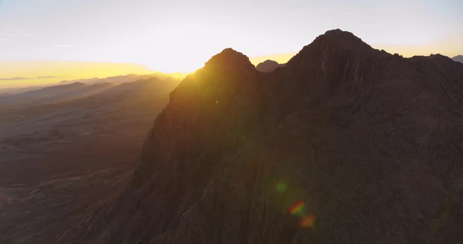 A stunning aerial view of the sun cresting over a majestic desert mountain range at sunrise