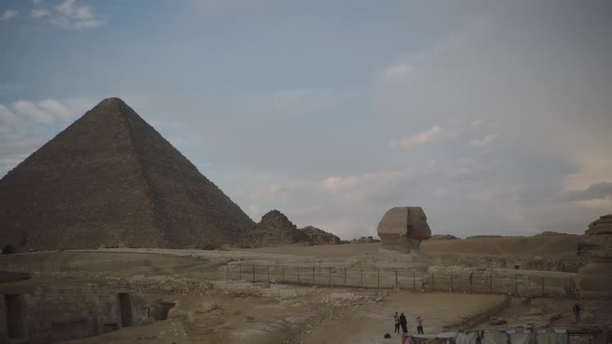 A slow pan reveals the majestic Great Sphinx and the Pyramid of Khafre standing in the desert at the Giza Necropolis in Egypt