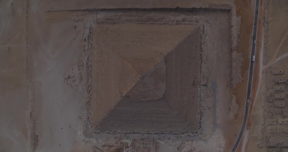 A slow, ascending birds-eye view reveals the peak of the Great Pyramid of Giza in the vast Egyptian desert