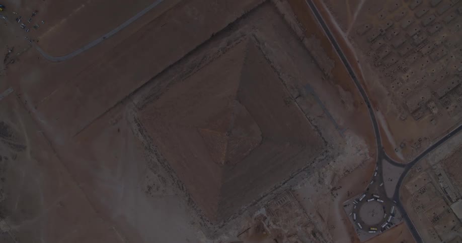 A slow, top-down aerial zoom reveals the majestic Great Pyramid of Giza standing alone in the vast Egyptian desert at twilight