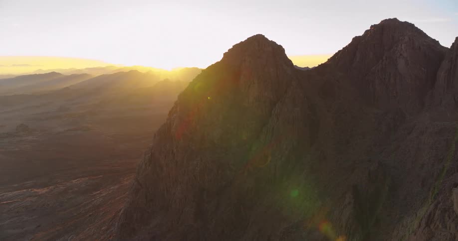 A majestic aerial view captures the sun rising over the rugged desert peaks of Mount Sinai