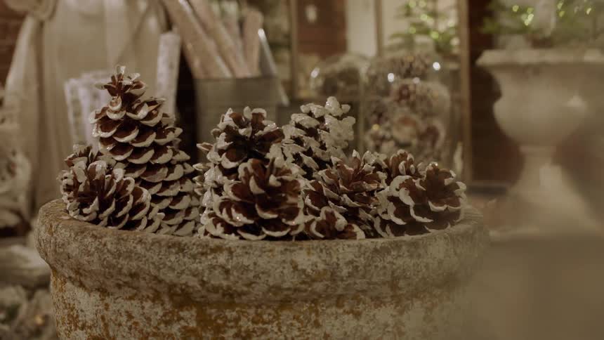 A bowl of pinecones sits near other christmas decorations