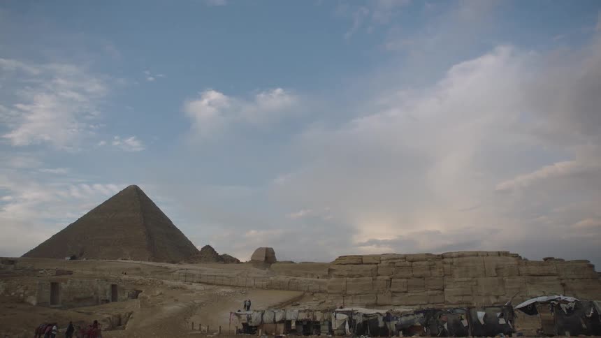 Wide static shot of the Great Pyramids and the Sphinx in the Giza desert under a cloudy sky
