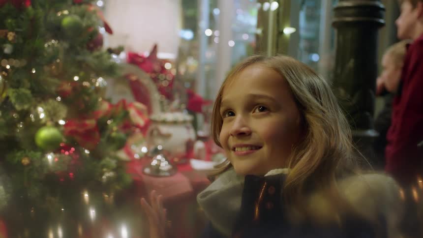 A girl stands by a christmas tree smiling