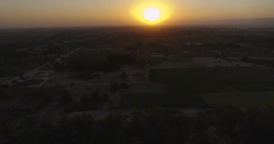 Aerial footage captures a stunning golden sunset over a rural landscape with unique dome-roofed buildings and sprawling farmlands