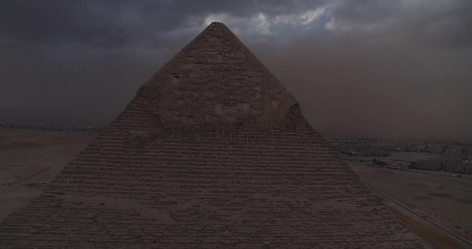 An ominous sandstorm gathers over the Great Pyramid of Giza in a dramatic aerial pullback shot