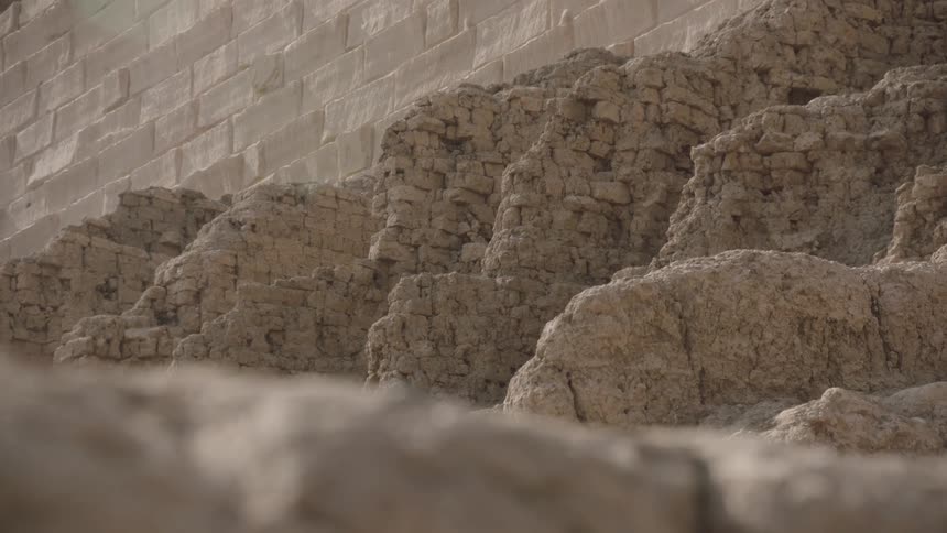 A slow-moving, low-angle shot reveals the weathered and crumbling texture of ancient stone ruins