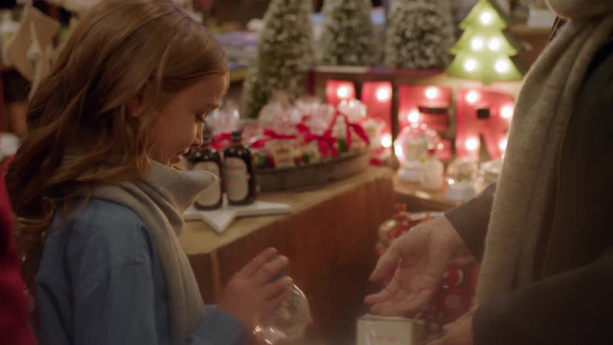 Woman hands a child a snow globe in a store