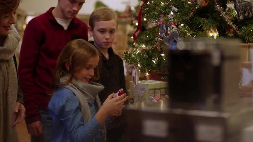 A girl pulls an ornament off the christmas tree