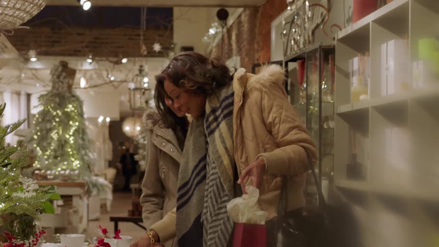 Two women walk through a shop selling christmas items