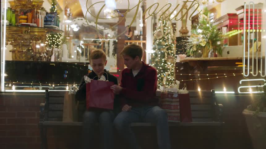 Two boys look in gift bags on a bench