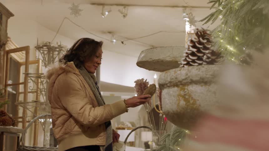 Woman holding gift bag looking at gifts in a shop during the day
