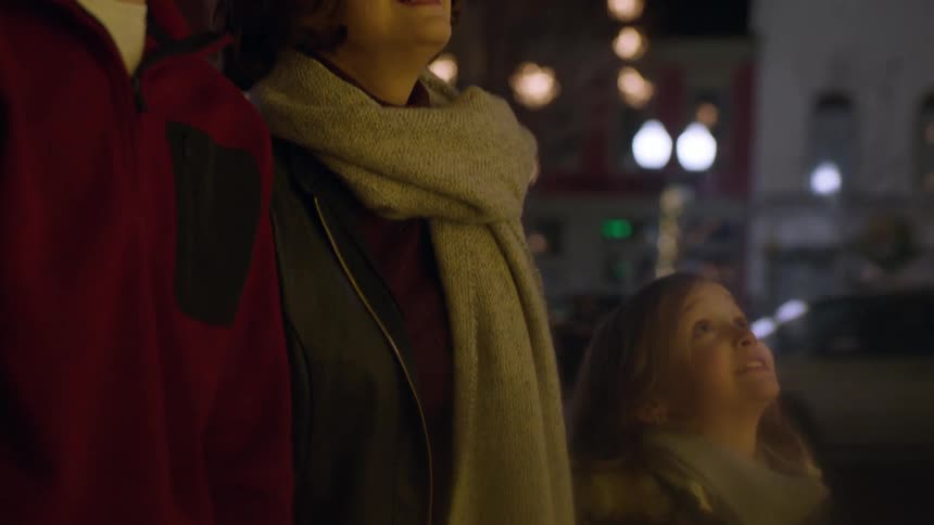 A family looking up in awe at something on an evening in a city