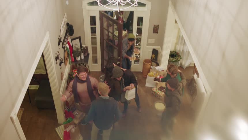 People greet each other at the front door while carrying presents