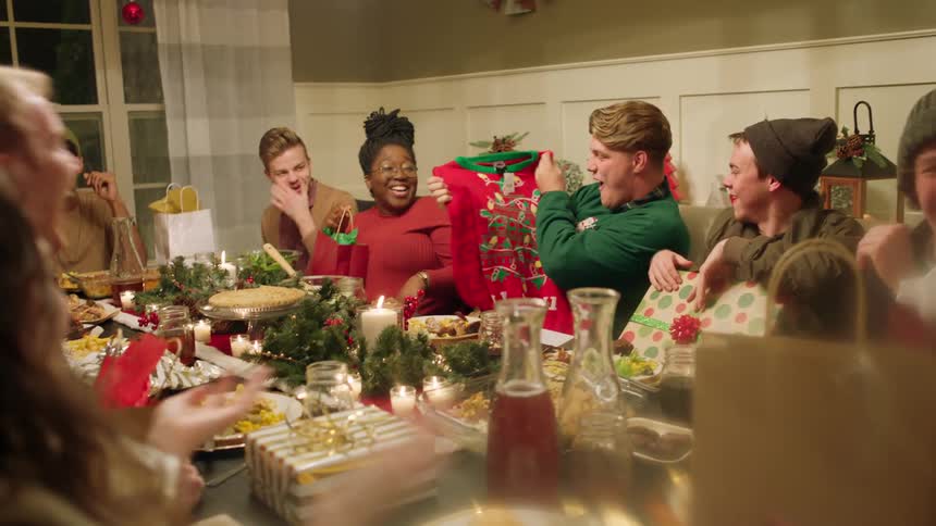 A man opens up a gift and pulls out a sweater