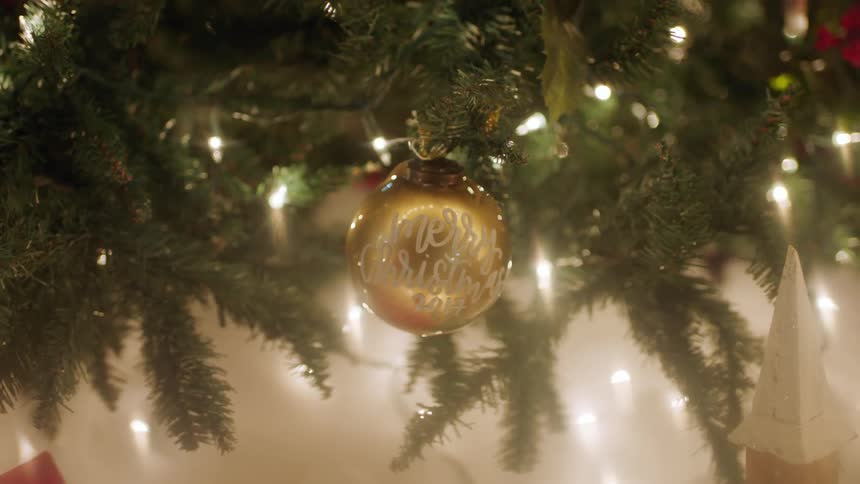 A gold ornament hangs from a christmas tree