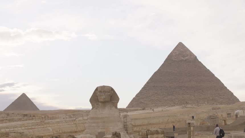 A slow tilt down reveals the majestic Great Sphinx and the Pyramids of Giza in the Egyptian desert