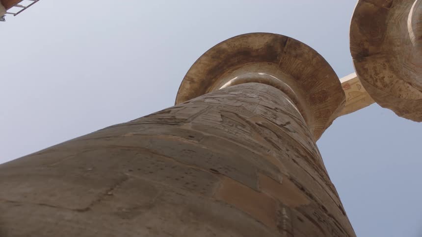 A static low-angle shot reveals the impressive scale of a carved stone pillar at an ancient Egyptian temple