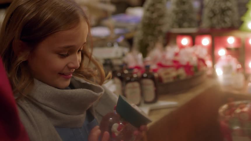 A girl shakes a snow globe in a store at christmastime
