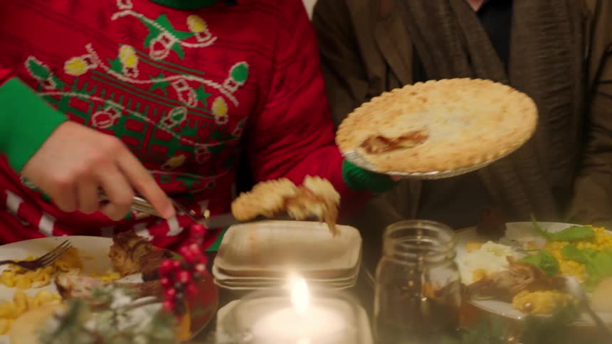 A man is dishing out pie at a dinner party