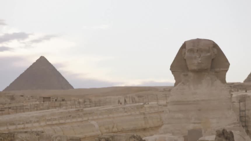 A focus pull reveals the Great Sphinx of Giza and the pyramids in the Egyptian desert on an overcast day