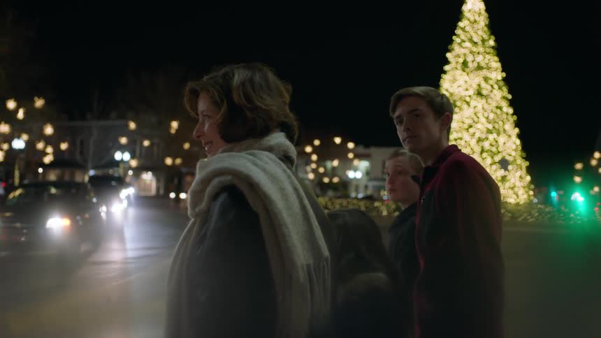 A family waits to cross a street near a christmas tree