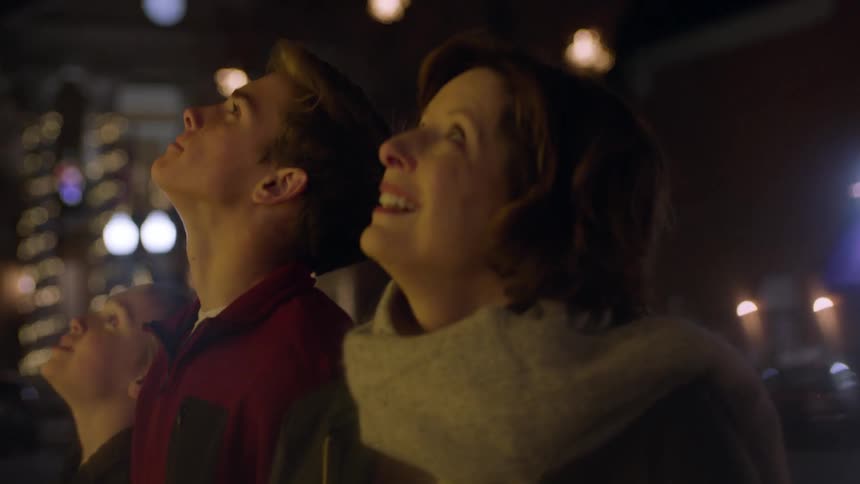 A family looks up at the night sky smiling