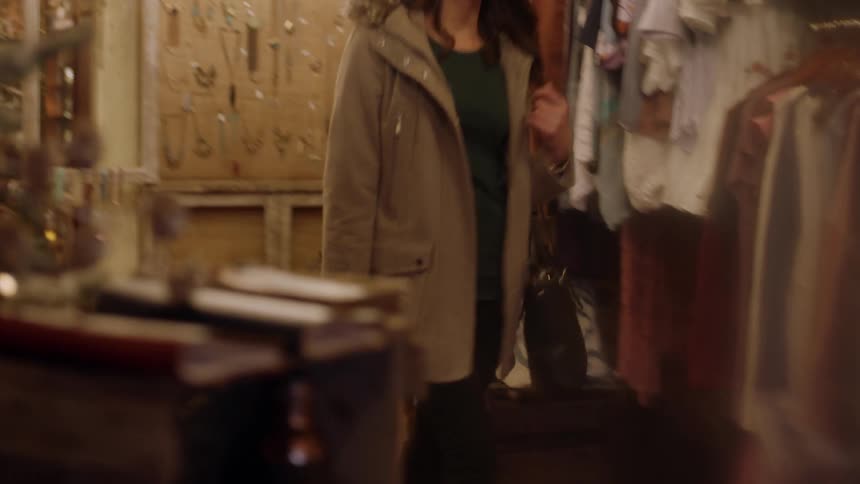 A woman walks past items in a shop smiling