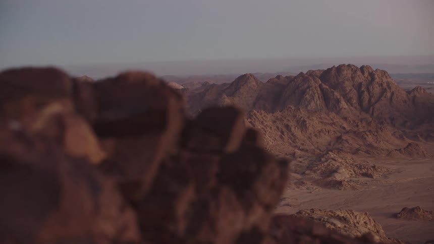 An epic, slow-moving shot reveals the vast and rugged mountain range of the Sinai desert at dawn