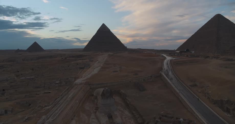 A majestic aerial view reveals the Great Sphinx and the Pyramids of Giza standing tall in the desert under a beautiful sunset sky