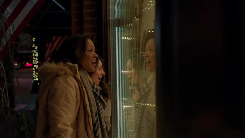 Two women stand in front of a shop window