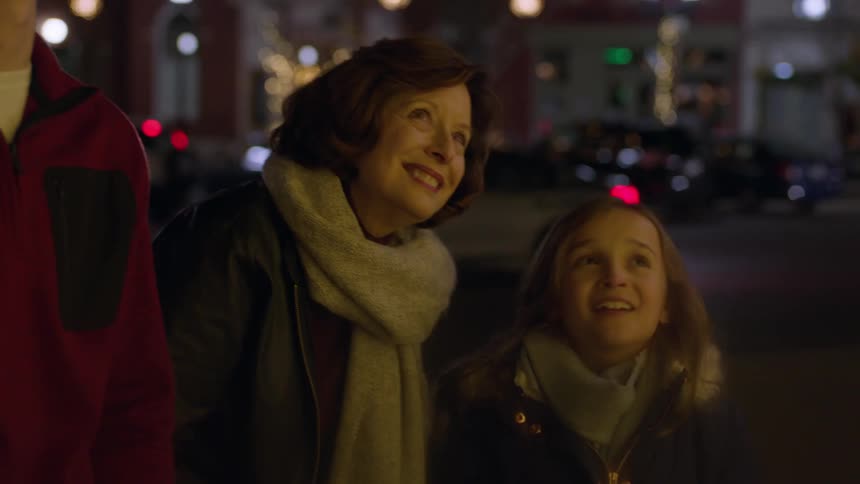 A woman points and talks with children while standing on a city sidewalk