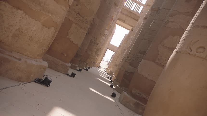 A static, canted angle shot captures the grandeur of the ancient stone columns and hieroglyphs within the Karnak Temple in Luxor, Egypt