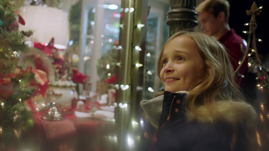 Little girl and her siblings looking at a window display in awe at christmas time