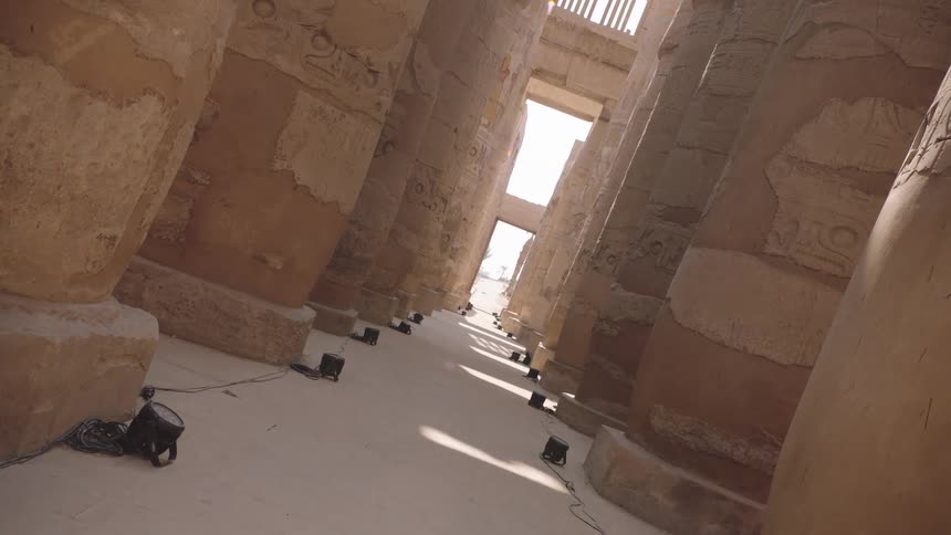 A slow, tilted dolly shot moves through the majestic Great Hypostyle Hall at the Karnak Temple in Egypt
