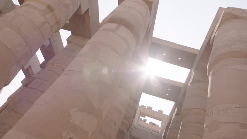 Sunlight streams through the massive, ancient columns of the Karnak Temple in Luxor, Egypt