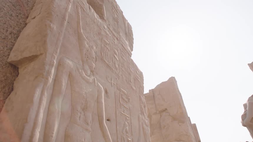 Close-up slow dolly shot of ancient Egyptian hieroglyphics carved on a stone temple wall under the bright sun