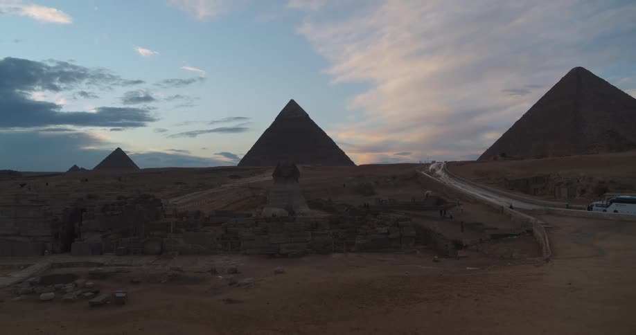 A slow aerial pullback reveals the magnificent Great Sphinx and the Pyramids of Giza during a beautiful sunset in Egypt
