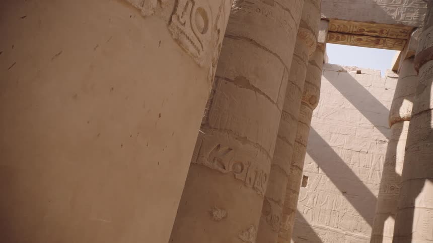 A slow dolly shot reveals intricate hieroglyphics carved into the massive stone pillars of an ancient Egyptian temple