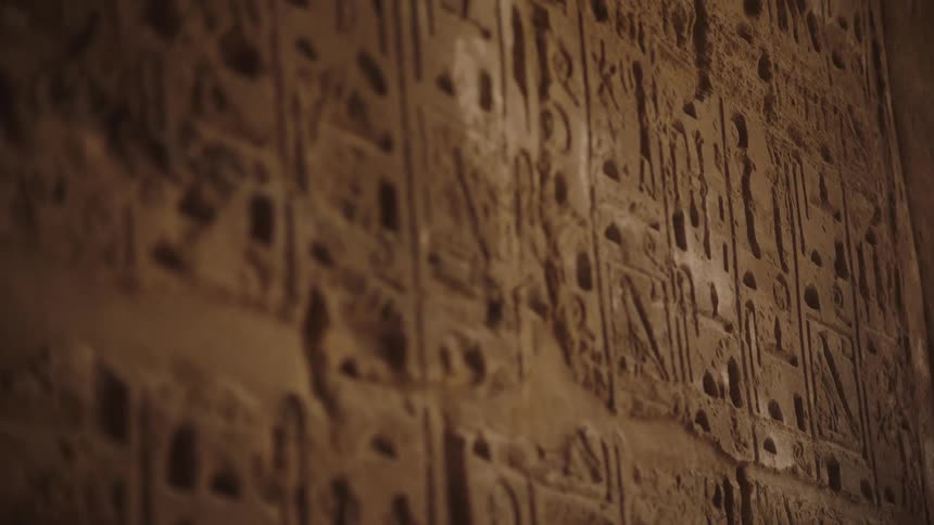 A slow-motion rack focus reveals detailed ancient Egyptian hieroglyphics carved into a stone wall