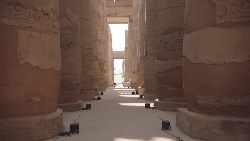 A slow dolly shot reveals the grand scale of massive, carved columns in the great hall of an ancient Egyptian temple